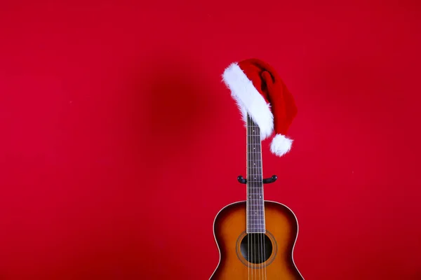 Concepto de música navideña. Guitarra acústica con cuerdas de acero y sombrero de Santa Claus . —  Fotos de Stock