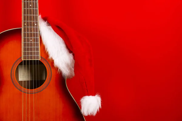 Concepto de música navideña. Guitarra acústica con cuerdas de acero y sombrero de Santa Claus . —  Fotos de Stock