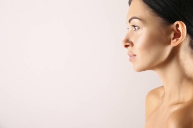 Gri arka planda poz veren sağlıklı ciltli güzel bir kadın..