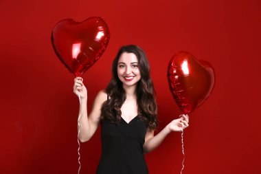 Sevgililer Günü tatili için elinde yüzen balonlar tutan güzel bir kadın..