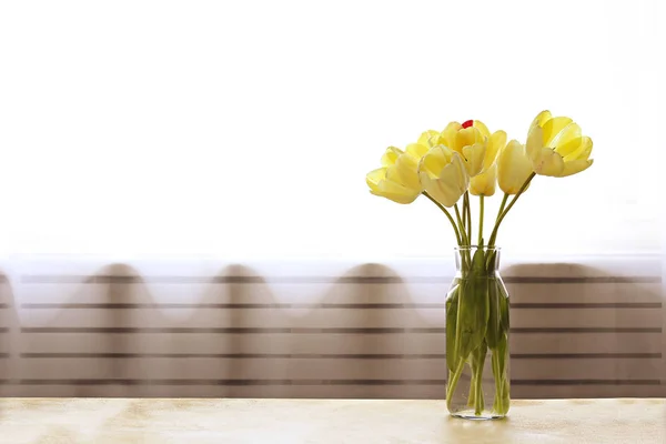 Ramo de flores de tulipán amarillo en jarrón de vidrio sobre mesa texturizada — Foto de Stock