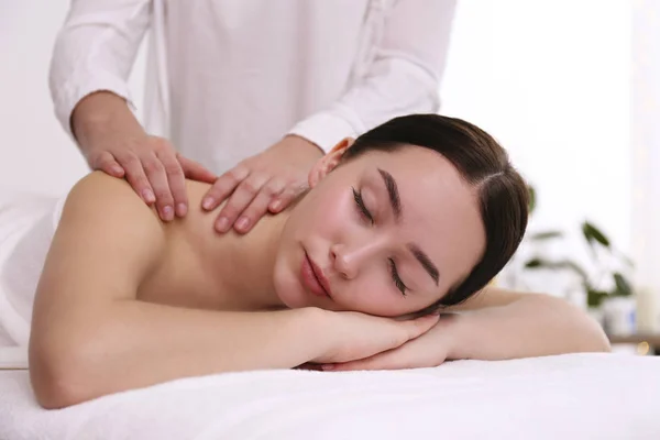 Brünette Frau mit entspanntem Gesichtsausdruck auf einem Massagetisch liegend. — Stockfoto