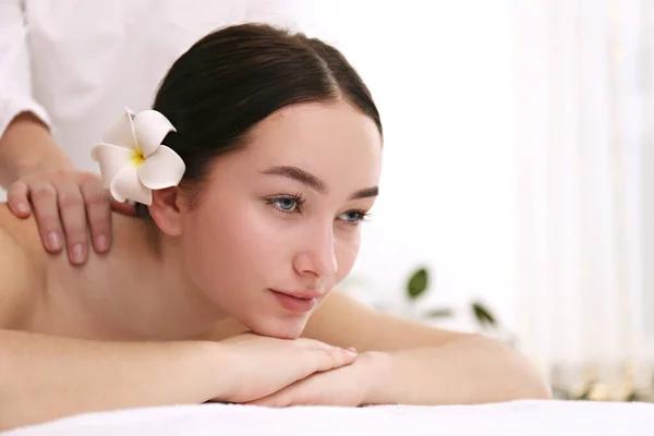 Mulher morena com expressão facial relaxada deitada em uma mesa de massagem . — Fotografia de Stock