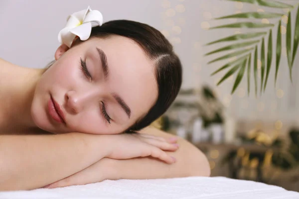 Mulher morena com expressão facial relaxada deitada em uma mesa de massagem . — Fotografia de Stock