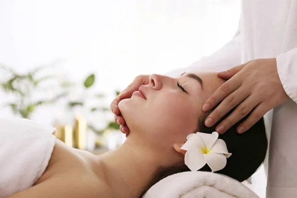 Brünette Frau mit entspanntem Gesichtsausdruck auf einem Massagetisch liegend. — Stockfoto