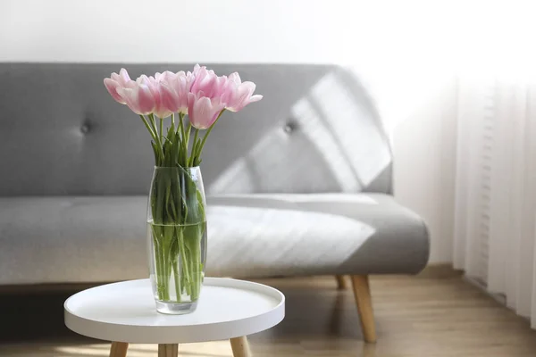 Glasvase mit Frühlingsblumen auf kleinem weißen Couchtisch. — Stockfoto