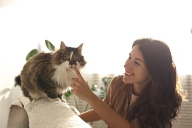 Charismatic young woman playing with her adorable cat.