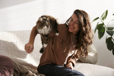 Charismatic young woman playing with her adorable cat.