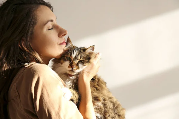 Charismatic young woman playing with her adorable cat.
