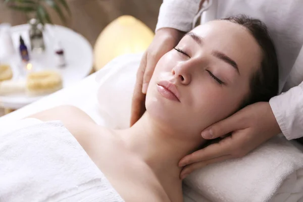 Brünette Frau mit entspanntem Gesichtsausdruck auf einem Massagetisch liegend. — Stockfoto