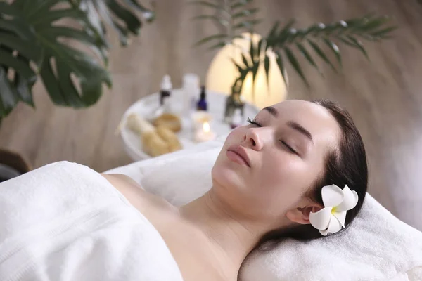 Mulher morena com expressão facial relaxada deitada em uma mesa de massagem . — Fotografia de Stock