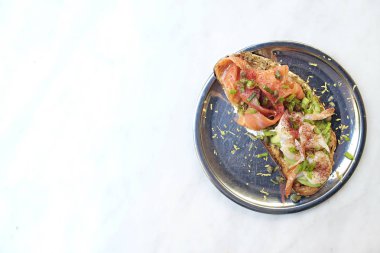 Tütsülenmiş somon, avokado, karides, krem peynir, zeytin ezmesi ve kapari ile yakın çekim. Çeşitli malzemelerle lezzetli deniz ürünleri bruschetta 'sı. Üst görünüm, kopyalama alanı, arkaplan.