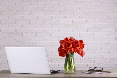 Taze çiçek kompozisyonu, siyah beyaz dizüstü bilgisayarlı bir buket Darwin melez lalesi, beyaz tuğla duvar arka planı. Ofis aşkı konsepti. Boşluğu kopyala, kapat, üst görünüm, düz yatış.