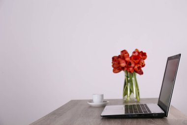 Taze çiçek kompozisyonu, siyah beyaz dizüstü bilgisayarı olan bir buket Darwin melez lalesi, beyaz duvar arkası. Ofis aşkı konsepti. Boşluğu kopyala, kapat, üst görünüm, düz yatış.