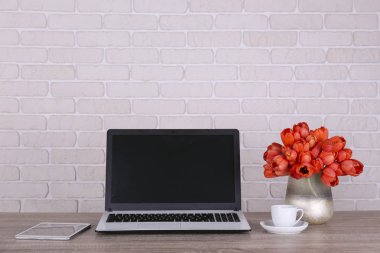 Taze çiçek kompozisyonu, siyah beyaz dizüstü bilgisayarlı bir buket Darwin melez lalesi, beyaz tuğla duvar arka planı. Ofis aşkı konsepti. Boşluğu kopyala, kapat, üst görünüm, düz yatış.