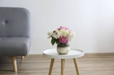 Minimum tavan arası tarzı iç dekorasyonu olan boş bir daire, ahşap zemin ve önünde şakayık demeti olan cam vazo ve arka planda yazı için bir sürü yeri olan boş bir duvar. Kapat..