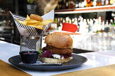 Nohut köfteli sebzeli burger, lahana turşusu, vejetaryen mayonezi ve yanında patates kızartması. Tabak servisi seçeneğiyle birlikte bedava fast food restoranı masası. Kapat, kopyala boşluk, arkaplan.