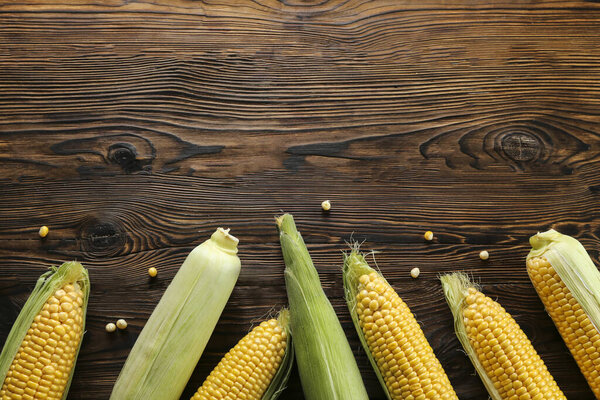 Куски спелой сырой кукурузы кладут на текстурированный стол из темного дерева. Концепция здорового летнего питания. Свежий сырой кукурузный початок. Чистое питание. Фон, вид сверху, крупный план, плоская кладка, копировальное пространство
.