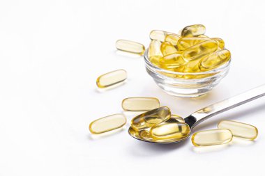 Omega 3 balık karaciğer yağı kapsülleri kaşık içinde. Tecrit edilmiş arka planda büyük altın saydam haplar. Her gün sağlıklı yağ asitleri besin takviyesi. Üst görünüm, düz görünüm, kopyalama alanı, kapat