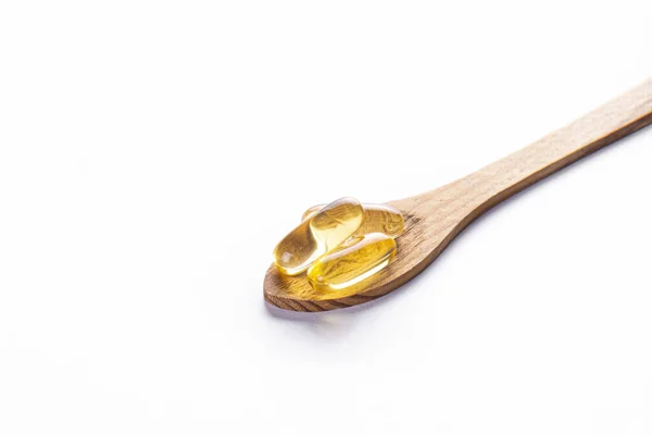 将欧米加3鱼肝油胶囊堆放在木勺中 大的金色半透明药丸在孤立的背景下 健康的日常脂肪酸营养补充剂 顶部视图 复制空间 — 图库照片