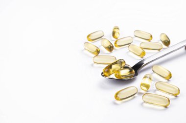 Omega 3 balık karaciğer yağı kapsülleri kaşık içinde. Tecrit edilmiş arka planda büyük altın saydam haplar. Her gün sağlıklı yağ asitleri besin takviyesi. Üst görünüm, düz görünüm, kopyalama alanı, kapat