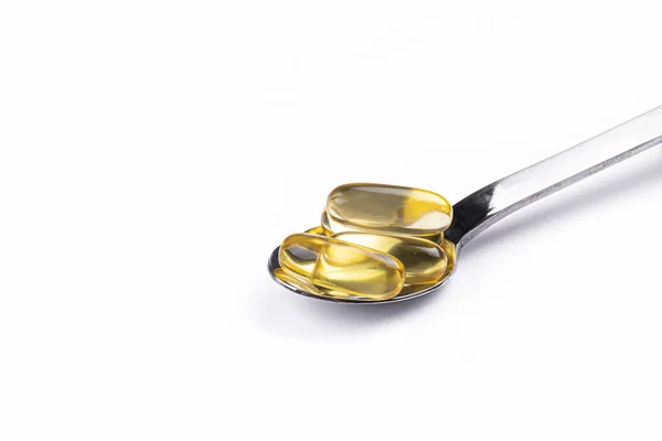 将欧米加3鱼肝油胶囊倒入勺子中 大的金色半透明药丸在孤立的背景下 每天健康的脂肪酸营养补充剂 顶部视图 复制空间 — 图库照片