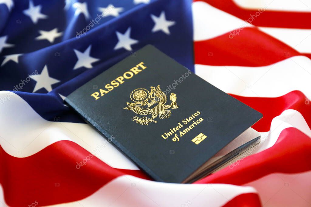 Latest version of United States of America citizen Passport with biometric ID chip on USA national flag. Person identification document. Close up, copy space, background, top view, flat lay.