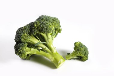 Temiz yeme konsepti. Bir grup olgun sulu taze koparılmış organik brokoli kafalar, beyaz arka planda izole edilmiş yeşil kaymak. Bahar detoksu için sağlıklı diyet. Çiğ vejetaryen yemeği. Kapat..