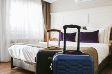 Genişletilmiş teleskopik saplı plastik kabuk valizi. Yolculuk için hazırlanmış iki bavul. Seyahat çiftleri konsepti. Otel odası yatak arka planı, metin için kopyalama alanı, kapat.
