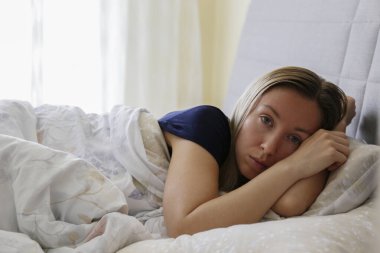 Depresyondaki bekar kadın dünya çapında karantina nedeniyle evde oturuyor. Yalnız bir kadının portresi yatağında yalnız başına strese girdi. Kapat, kopyala boşluk, arkaplan.