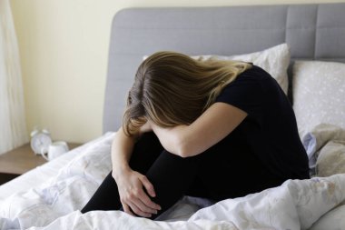 Depresyondaki bekar kadın dünya çapında karantina nedeniyle evde oturuyor. Yalnız bir kadının portresi yatağında yalnız başına strese girdi. Kapat, kopyala boşluk, arkaplan.