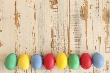 Bir sürü boş Paskalya yumurtası, farklı parlak renklerde, grunted ahşap dokuma sehpası üzerinde ve metin için bir sürü kopya alanı var. Üst manzara, düz yatak, yakın çekim..