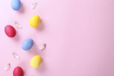 Pembe kağıtta farklı renkte boyanmış Paskalya yumurtaları ve metin için bir sürü kopya alanı var. Üst manzara, düz yatak, yakın çekim..