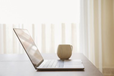 Merkez ofis konsepti. Oturma odasındaki çalışma alanından. Modern laptop ve bir fincan sıcak içecek ahşap masada. Kapat, kopyala boşluk, arkaplan.