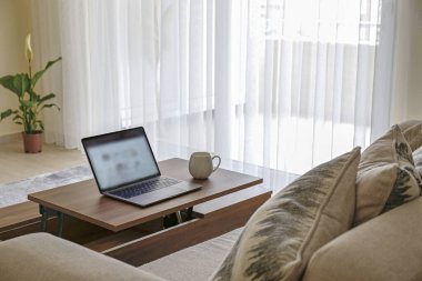 Merkez ofis konsepti. Oturma odasındaki çalışma alanından. Modern laptop ve bir fincan sıcak içecek ahşap masada. Kapat, kopyala boşluk, arkaplan.