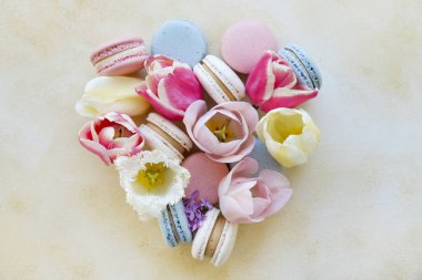 Geleneksel Fransız badem kurabiyeleriyle kadınsı kompozisyon ve sarı grunge beton desenli arka planda yumuşak lale çiçekleri. Üst görünüm, kapat, boşluğu kopyala.