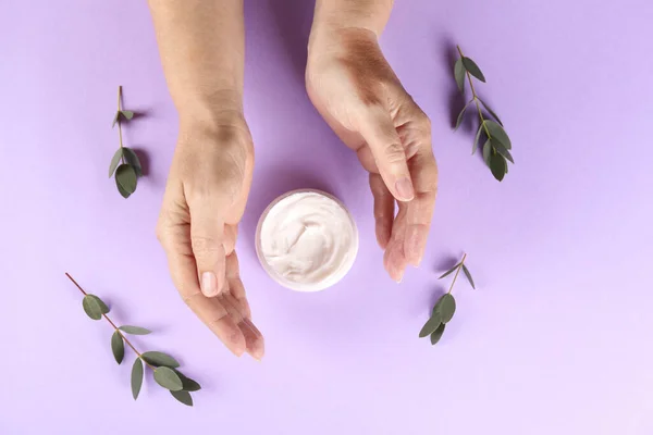 Revitalizing hand cream for healing and recovery after excessive use of soap and disinfectants. Adult woman applying moisturizing lotion. Copy space, close up, background, flat lay, top view.