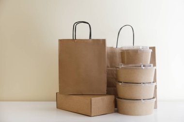 Paketlenmiş yiyecek paketleri ve markanın logosu için fotokopi alanı olan kutularla dolu boş tek kullanımlık konteynırlar. Masaya karton kaseler koymak için çevre dostu yakın çekim.