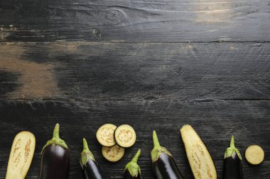Bir grup olgun organik cilalanmış patlıcan homurdanmış ahşap arka planda bir araya getirilmiş. Masada patates sebzesi var. Temiz yeme konsepti. Arkaplan, kapat, düz yat, üst manzara.