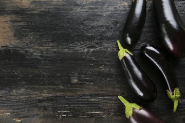 Bir grup olgun organik cilalanmış patlıcan homurdanmış ahşap arka planda bir araya getirilmiş. Masada patates sebzesi var. Temiz yeme konsepti. Arkaplan, kapat, düz yat, üst manzara.