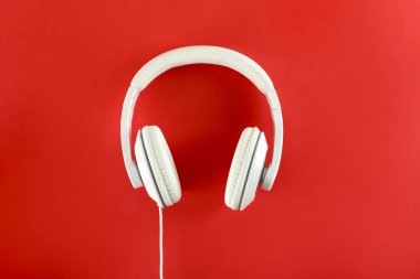 Minimalist üst görünüm kompozisyonu, beyaz kulaklıklar ve parlak kağıt kaplamalı arka plan. Metnin için bir sürü kopya alanı var. Yaklaş, düz yat..