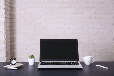 Bir blogcunun yaratıcı çalışma alanı. Beyaz dizüstü bilgisayar, ahşap masada, çatı katı tarzı, tuğla duvarlı. Tasarımcının masa konsepti. Kapat, kopyala boşluk, arkaplan.