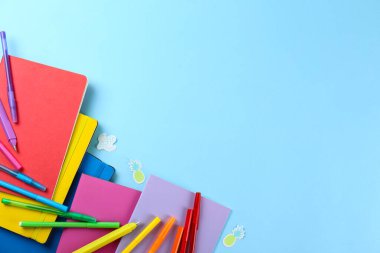 Okul konseptine geri dönelim. Farklı okul gereçleri, defter, kalem, arka planda mavi kağıtlı aksesuarlar. Bir sürü kırtasiye malzemesi. Kapat, boşluğu kopyala, üst görünüm, düz yatış.
