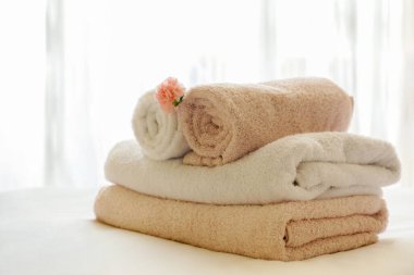 Yeni yapılmış yatağı, mükemmel temiz ve ütülenmiş çarşafları, katlanmış havluları ve doğal güneş ışığının süslemesi için tek çiçekli bir otel odası. Kapat, metin için boşluk kopyala.