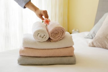 Hizmetçi kadın otel odasındaki katlanmış ve istiflenmiş havluları değiştiriyor. Temiz ve ütülenmiş çarşaflar güneş ışığında. Kapat, metin için boşluk kopyala.