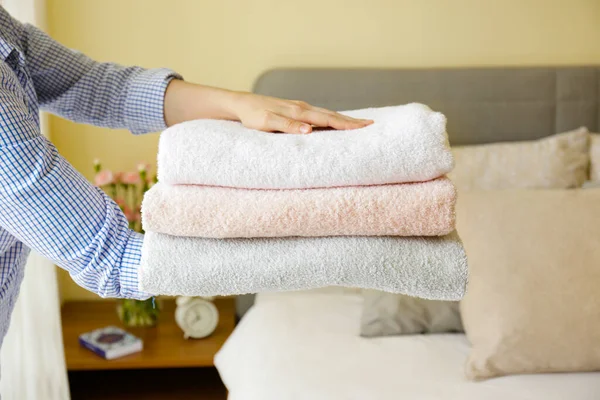Hizmetçi kadın otel odasındaki katlanmış ve istiflenmiş havluları değiştiriyor. Temiz ve ütülenmiş çarşaflar güneş ışığında. Kapat, metin için boşluk kopyala.
