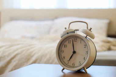 Uyan ve parla konsepti. Sabah 7: 00 'de sabah ışıklarıyla yapılmamış yatağı gösteren beyaz alarmlı saati yakından çek. Kapat, kopyala boşluk, arkaplan.