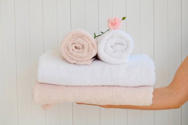 Kat görevlisi kadın katlanmış ve istiflenmiş havlu setini tutuyor. Oda servisindeki kadın temiz çamaşırları tutuyor. Kapat, metin ve arkaplan için boşluk kopyala.