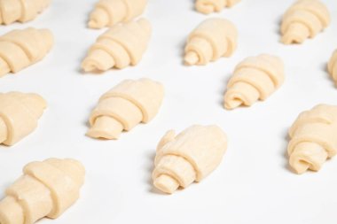 Beyaz arka planda izole edilmiş kruvasan pişirmeye hazır yarı donmuş halde stüdyo çekimini kapat. Pişmemiş geleneksel Fransız pastası. Boşluğu kopyala, üst görünüm.