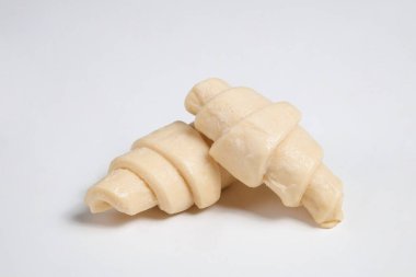 Beyaz arka planda izole edilmiş kruvasan pişirmeye hazır yarı donmuş halde stüdyo çekimini kapat. Pişmemiş geleneksel Fransız pastası. Boşluğu kopyala, üst görünüm.